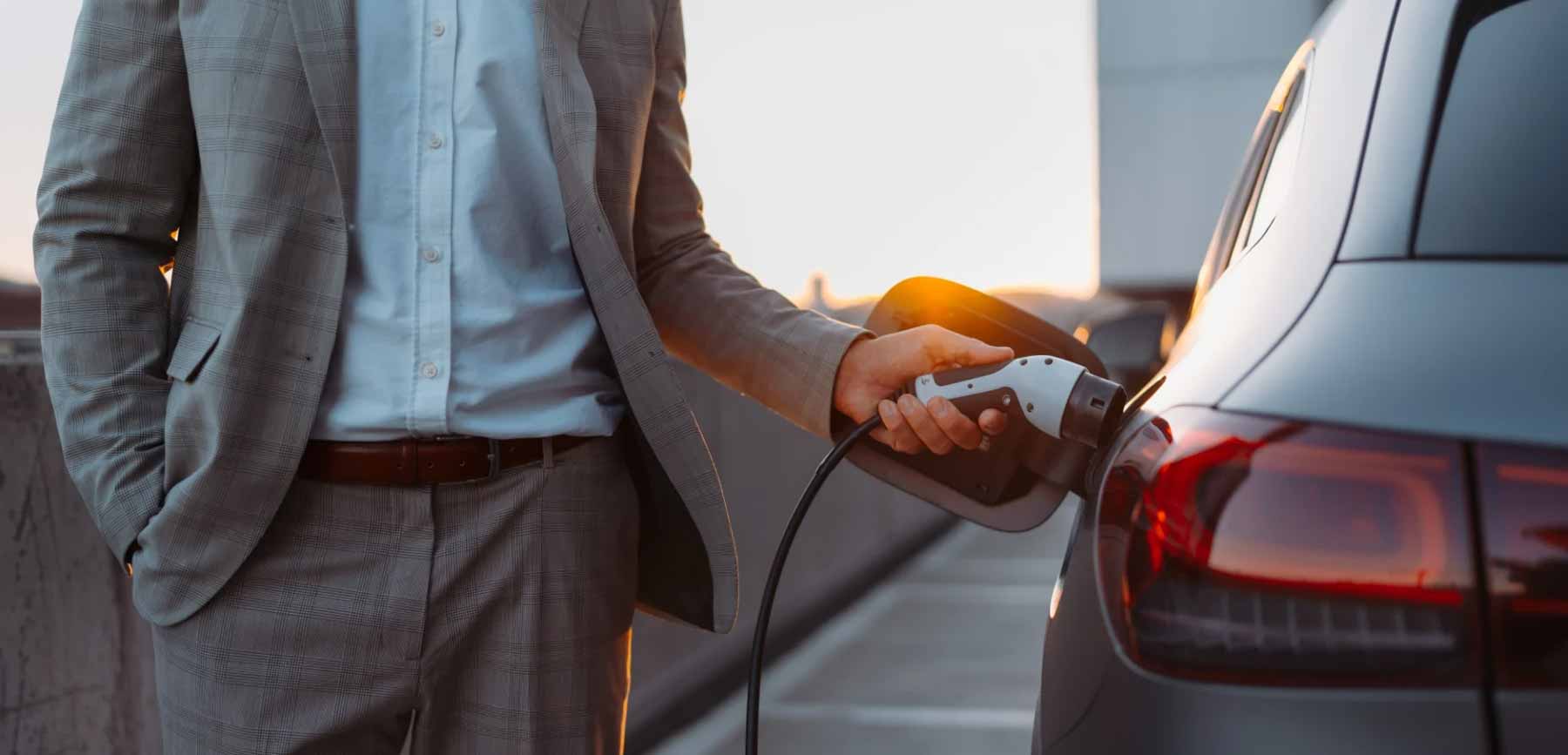 A business man charging his EV at the workplace