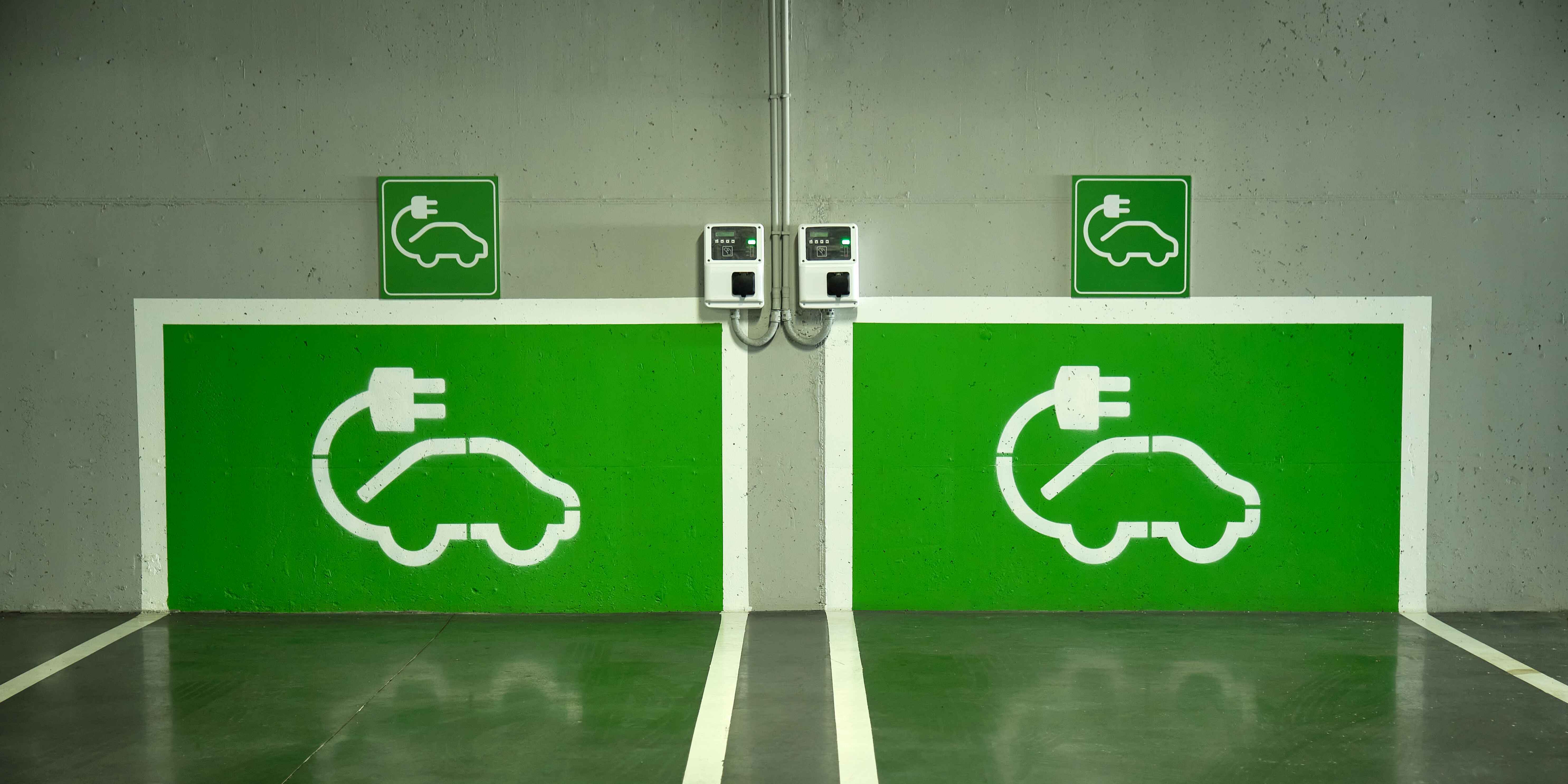 Green-colored EV charging signs clearly marked on the wall, indicating charging station locations.